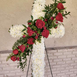 Tall standing white cross arrangement with red roses on a metal easel