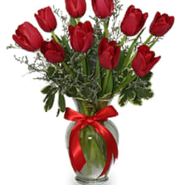 Red tulip arrangement in a clear glass vase with a red ribbon bow