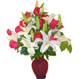 Arrangement of red roses and white lilies in a red glass vase