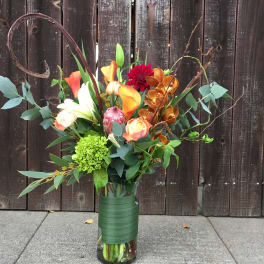 Tall mixed bouquet with calla lilies, orchids, and dahlias in a glass vase