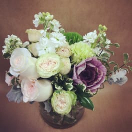 White and pale pink roses with purple cabbage in a glass vase
