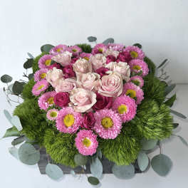 Pink roses and daisies arranged in a low rectangular box