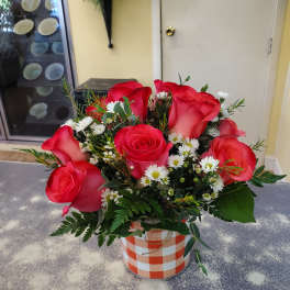 Bouquet of red roses and white daisies in a checkered container