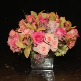 Pink and peach roses with orchids in a clear glass vase