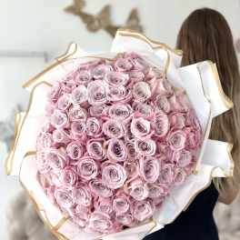 Large bouquet of pale pink roses wrapped in white paper with gold trim