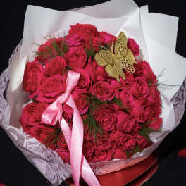 Bouquet of bright pink roses wrapped in white paper with a pink ribbon