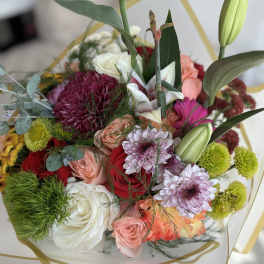 Mixed bouquet of roses, chrysanthemums, and lilies in white wrapping