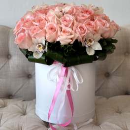 Pink roses and white orchids arranged in a white hat box
