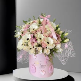 Pink and white bouquet in a pink hatbox with baby-themed decorations