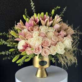 Pink and white roses with lilies in a gold vase