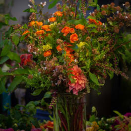 Tall mixed bouquet with orange roses and pink dahlias in a glass vase