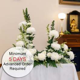 White chrysanthemum sympathy arrangement on a draped table in a ceremonial setting