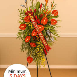 Tall tropical sympathy standing spray with red-orange flowers on an easel
