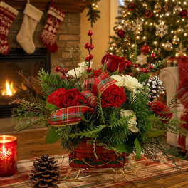 Christmas bouquet with red and white flowers in a basket, decorated with plaid ribbon