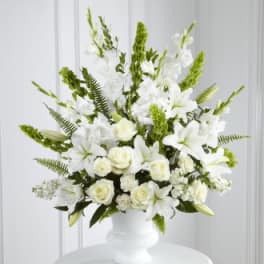 White floral arrangement in a white vase with green accents