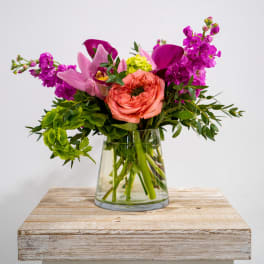 Pink and purple flowers arranged in a clear glass vase