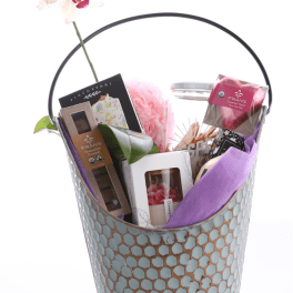 Gift basket with chocolates, candles, and a pink orchid stem
