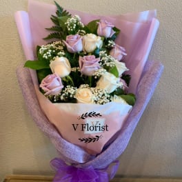 Bouquet of pale pink and white roses wrapped in pink paper