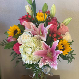 Bouquet of pink lilies, roses, hydrangea, and sunflowers in a glass vase