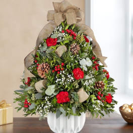 Christmas arrangement in a white vase with red flowers and pinecones