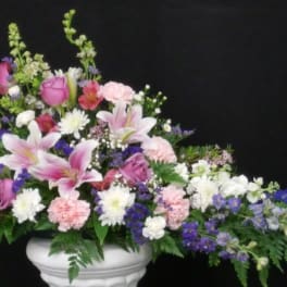 Pink and white mixed flower arrangement in a white pedestal vase