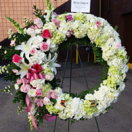 Heart-shaped floral wreath with pink and white flowers on an easel