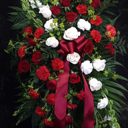 Standing floral spray with red and white roses and carnations on a black background