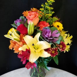 Mixed bouquet with lilies, roses, and daisies in a glass vase