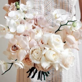 Bouquet of pale roses and white orchids held in hand