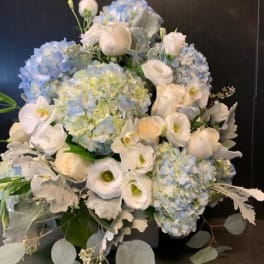 Blue hydrangeas and white roses arranged with silver foliage