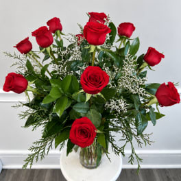 Red roses arranged in a clear glass vase with white filler flowers