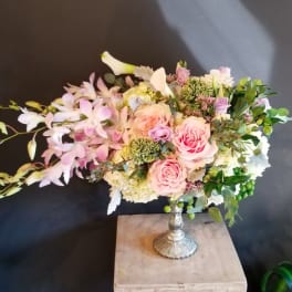 Pink roses and pale orchids arranged in a silver vase