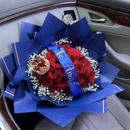 Red rose bouquet wrapped in blue paper with a crown topper
