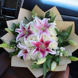 Bouquet of pink lilies and white roses wrapped in tan paper