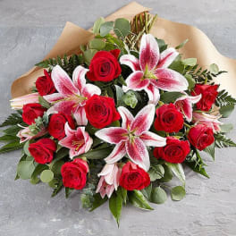 Bouquet of red roses and pink lilies wrapped in tan paper