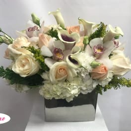 Cream roses and calla lilies in a square vase
