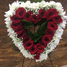 Heart-shaped red rose and white daisy wreath on a stand