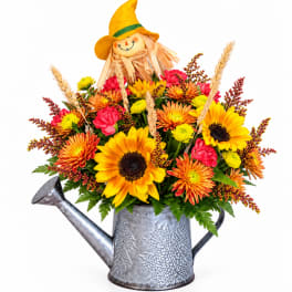Fall bouquet in a metal watering can with a scarecrow topper