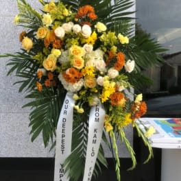 Large standing floral wreath with yellow, white, and orange flowers
