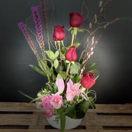 Tall floral arrangement with red roses and pink lilies in a white vase