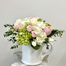 Pink and white roses with hydrangeas in a white mug vase