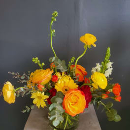 Yellow and orange mixed flower arrangement in a glass vase
