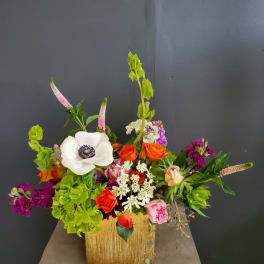 Colorful mixed flower arrangement in a gold square vase