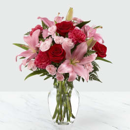Pink lilies and red roses arranged in a clear glass vase