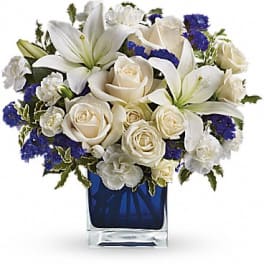 White lilies and roses arranged in a blue glass vase