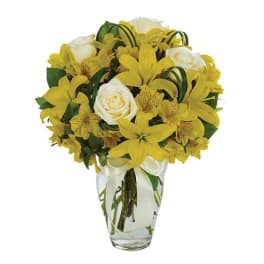 Yellow and white bouquet in a clear glass vase with a white ribbon
