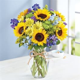 Bouquet of sunflowers and purple flowers in a clear glass vase