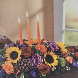 Floral centerpiece with orange candles and sunflowers