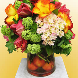 Bouquet of multicolored roses, hydrangea, and green viburnum in a glass vase