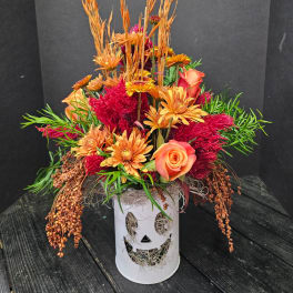 Orange and red floral arrangement in a white pumpkin vase